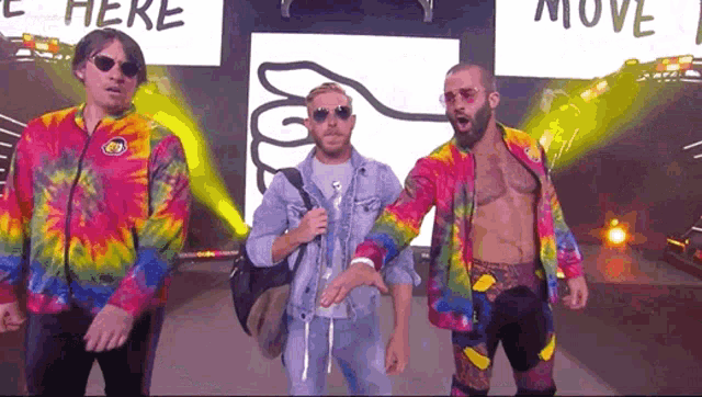 three men are standing in front of a sign that says move here
