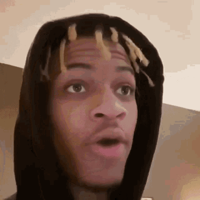 a close up of a man wearing a hoodie with dreadlocks on his head .