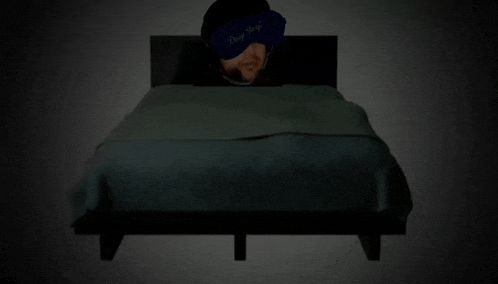 a man wearing a sleep mask is laying in bed