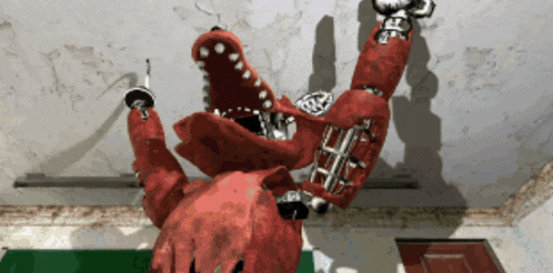 a red robot with a sword in its mouth is laying on its back