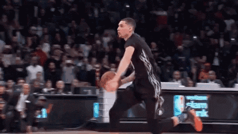 a basketball player is dribbling a ball on a court in front of a verizon sign .