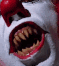 a close up of a clown 's mouth with a red nose .