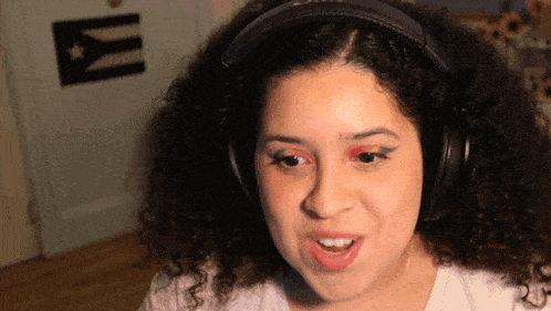 a woman wearing headphones is making a funny face in front of a cuban flag