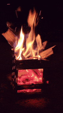 a fire is burning in a small metal box with a glass door