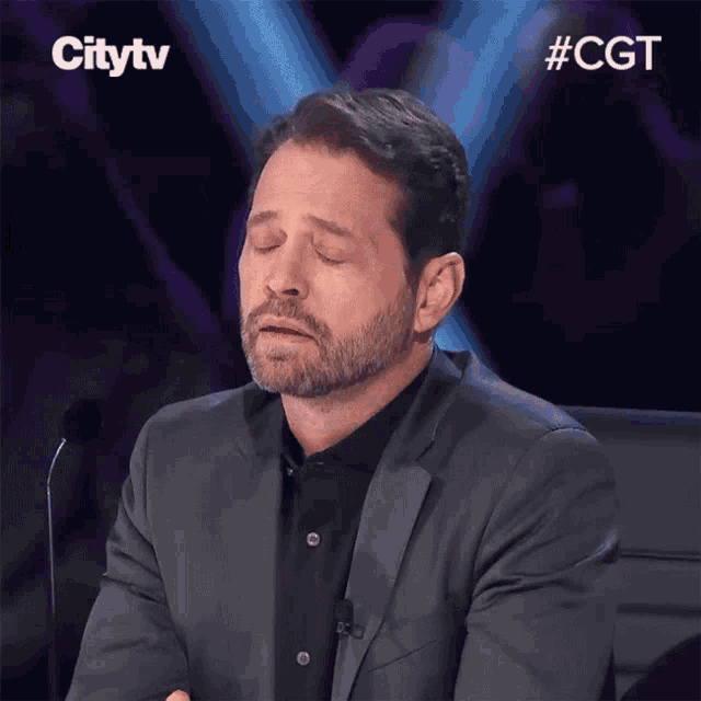 a man sitting in front of a microphone with his eyes closed and a citytv logo behind him