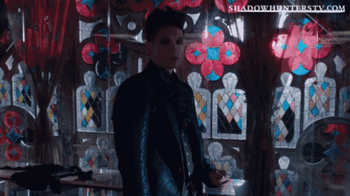 a man standing in front of a stained glass window with the website shadowhunterstv.com visible