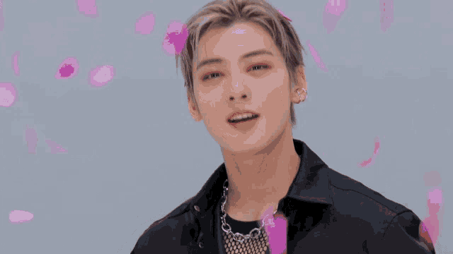 a close up of a person 's face with pink petals falling around him