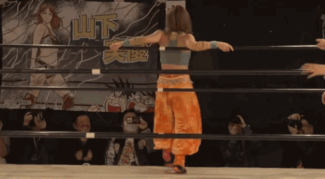 a woman stands in a wrestling ring in front of a sign that says ' u.t. '
