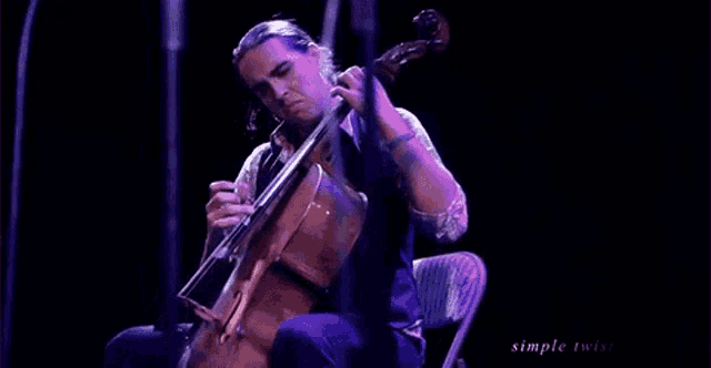 a man is playing a cello on a stage .