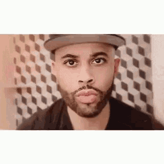 a man with a beard wearing a hat and making a funny face .