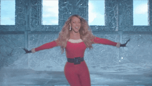 a woman in a santa outfit is dancing in front of a window