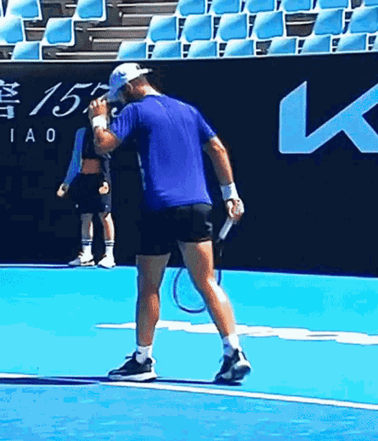 a man in a blue shirt is holding a tennis racquet on a blue tennis court