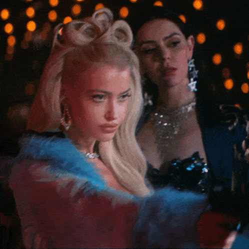 a woman in a blue fur coat is standing next to another woman in a black dress