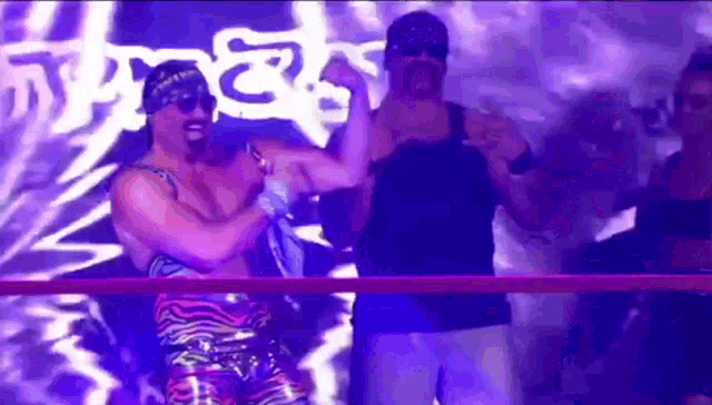 two wrestlers are standing in a ring with purple lights behind them .