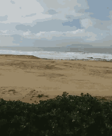 a sandy beach with a blue sky and waves