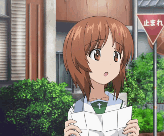 a girl is holding a piece of paper in front of a sign that says " stop "