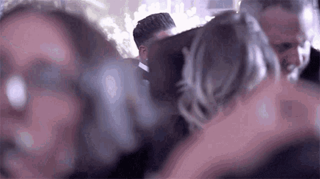 a group of people are dancing at a wedding reception and a man is holding a woman 's arm .