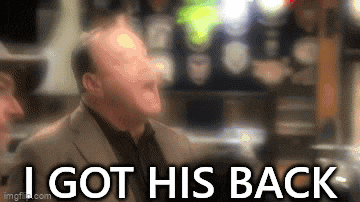a man in a suit is laughing in a bar with the words `` i got his back '' .
