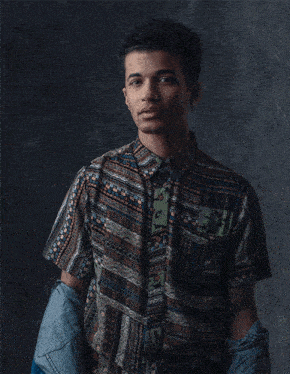 a young man wearing a denim jacket and a shirt with a pattern that says ' a ' on it