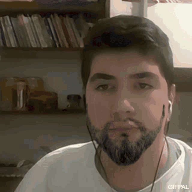 a man with a beard wearing ear buds and a white shirt