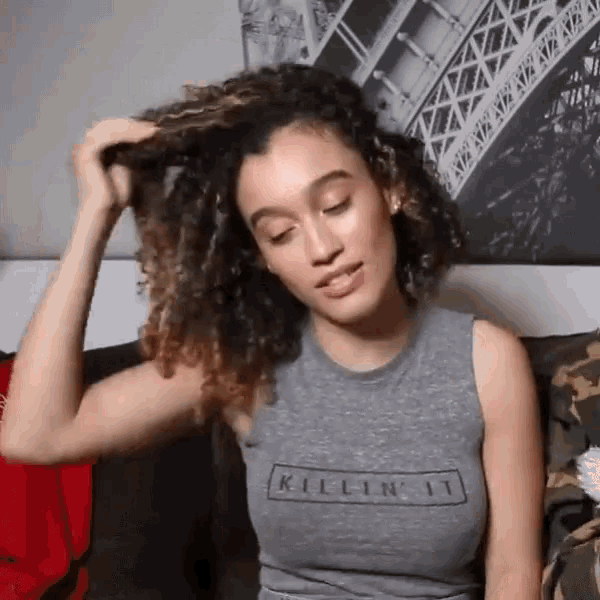 a woman with curly hair wearing a killin ' it shirt