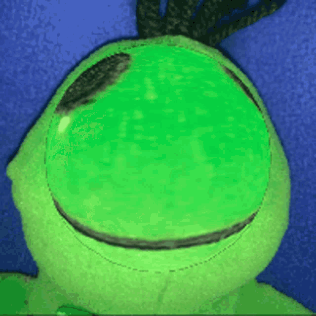 a green stuffed animal with a smiley face