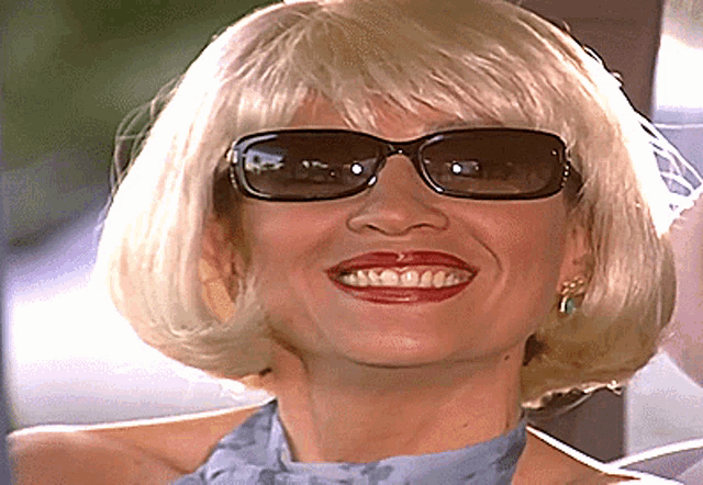 a woman wearing sunglasses and a wig smiles