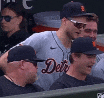 a man wearing a jersey that says detroit is sitting in the dugout