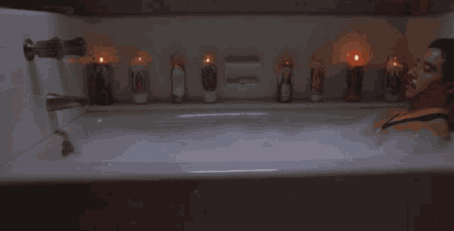 a man is taking a bath in a bathtub with candles in the background