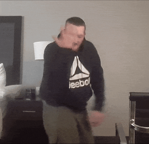 a man wearing a reebok sweatshirt is dancing