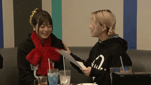 a woman wearing a black hoodie with the number 2 on it holds a piece of paper