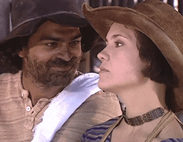 a man with a beard and a woman wearing a cowboy hat are looking at each other