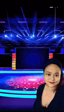 a woman is taking a selfie in front of a stage with a lot of lights .