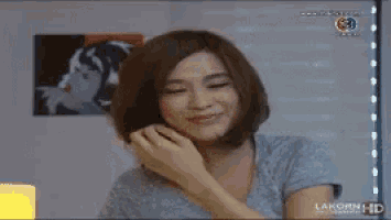 a woman is covering her mouth with her hand in front of a tv screen that says lakorn hd .