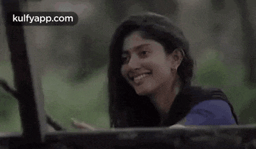 a woman is smiling while sitting in the back of a truck .
