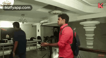a man in a red shirt is standing next to another man in a blue shirt in an office .