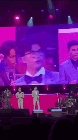 a man in a suit and bow tie is standing on a stage