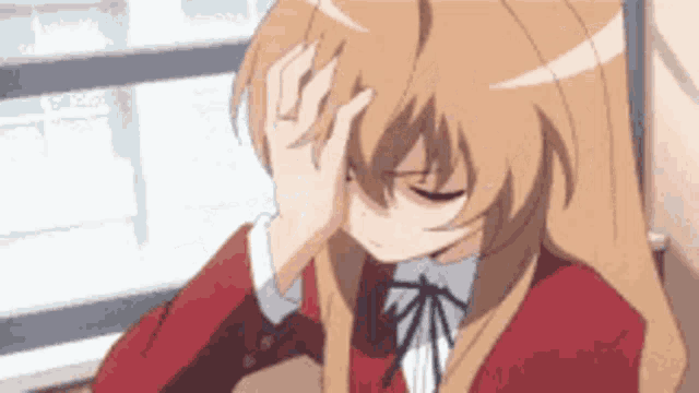 a girl is sitting at a table holding her head .