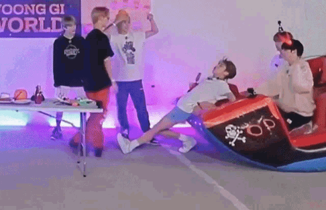 a group of young men are standing around a table while a man is sitting on a boat .
