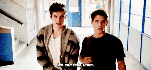two boys are standing next to each other in a hallway and one of them is saying `` we can take them '' .