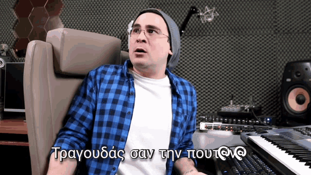 a man in a blue plaid shirt is sitting in front of a keyboard with a foreign language written on it