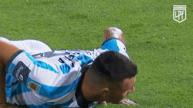 a soccer player is laying on the grass and his jersey says sucre on the armband