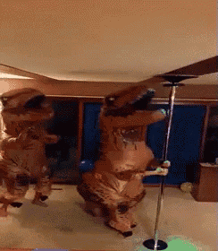 two people dressed in t-rex costumes are dancing on poles