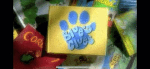 a yellow box with a blue paw print on it that says ' blue 's clues ' on it .