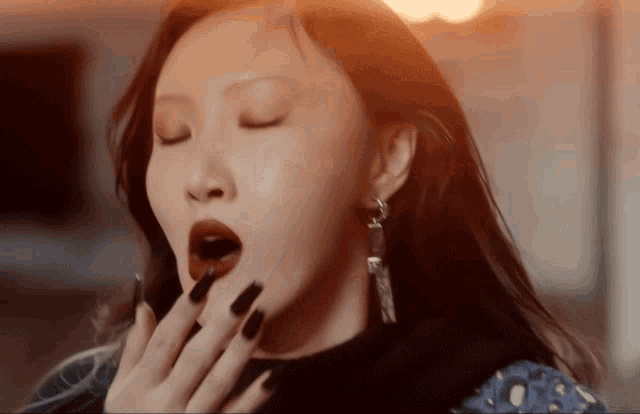a woman with black nails and red lipstick yawning with her eyes closed