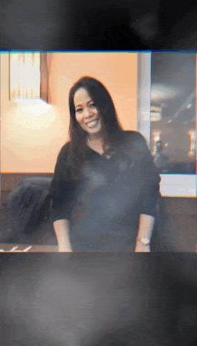 a woman in a black shirt is smiling in a blurry photo