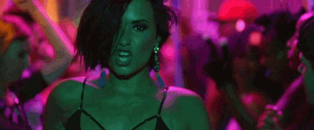 a woman is dancing in a club with purple lights and a man wearing a hat with the number 191 on it .