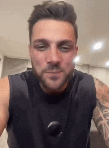 a man with a beard is wearing a black tank top and has a tattoo on his arm .