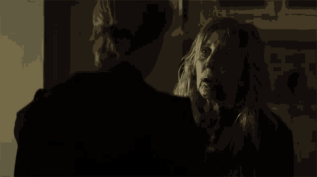 two women are standing next to each other in a dark room talking to each other .