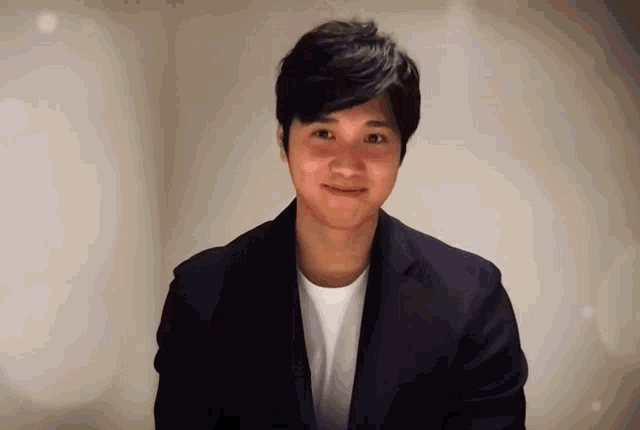a young man in a suit and white shirt smiles at the camera
